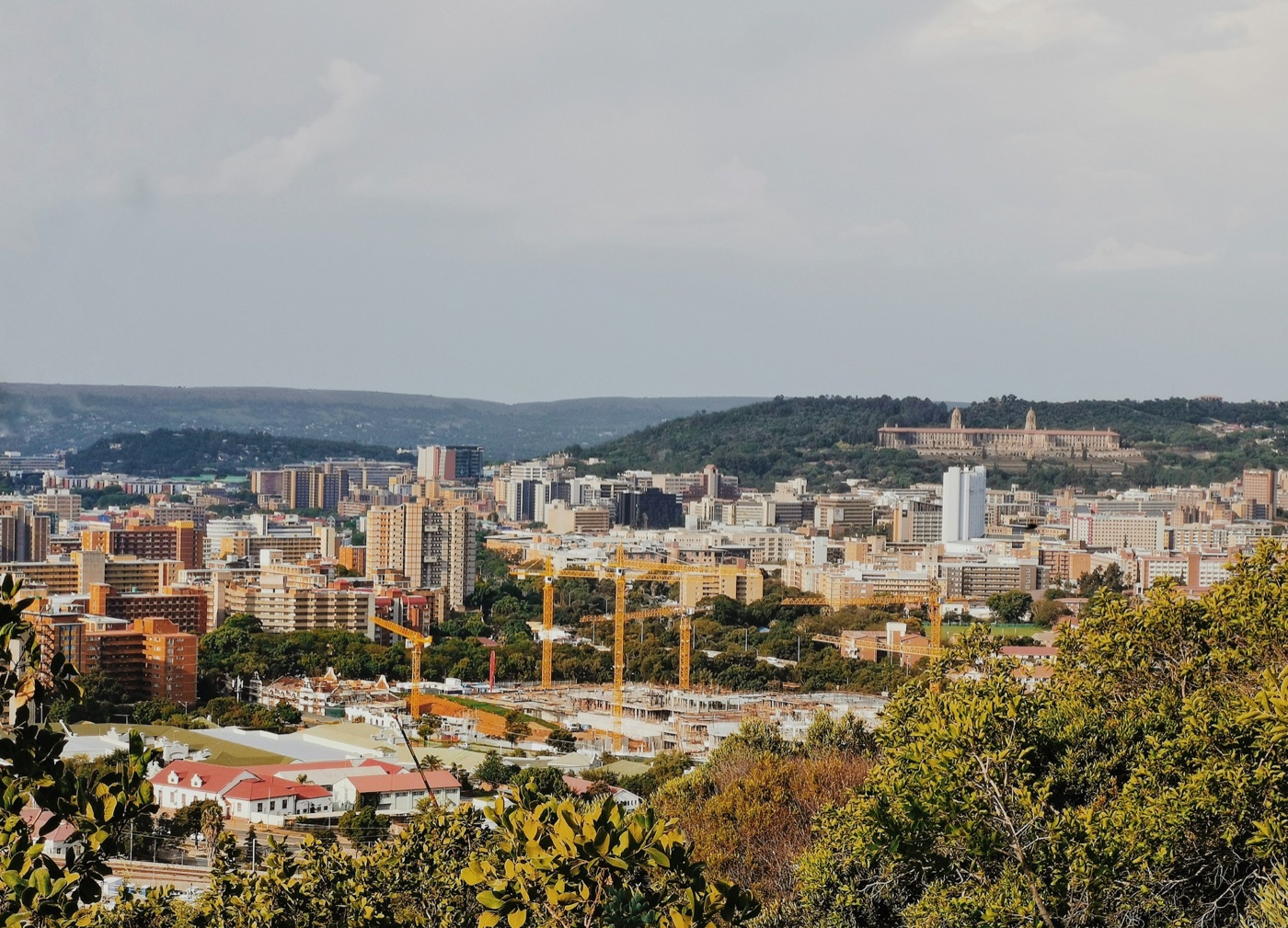 Pretoria seen from the surrounding hills, the Union Buildings on the ridge and construction cranes across the city
